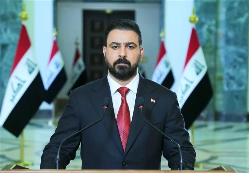 Irak bayraklarının önünde açıklama yapan üst düzey Iraklı yetkili; Bağdat, ABD ve Suudi Arabistan’ın ortak saldırısını Irak’ın egemenliğinin açık bir ihlali ve ülkenin resmî güvenlik kurumlarına yönelik bir saldırı olarak kınadı.