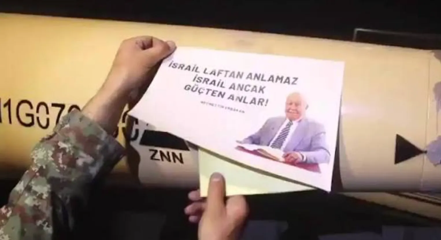 Bir füzenin üzerine, Necmettin Erbakan'ın fotoğrafının ve kendisine atfedilen "İsrail laftan anlamaz; İsrail ancak güçten anlar." sözünün yer aldığı bir afişin yapıştırıldığı anı gösteren görüntü. Bu kare, 2026 yılında İran ile İsrail arasında yaşanan savaş sırasında yayımlandı ve Erbakan'ın Siyonizm karşıtı duruşuna ve Filistin davasına verdiği desteğe yapılan sembolik bir gönderme olarak yorumlandı.