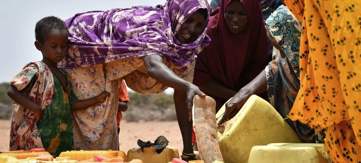 Kuraklık ve su kıtlığından etkilenen bir bölgede su dağıtım noktasında bidonlarını dolduran Somalili kadınlar; iklim krizinin gıda güvenliği ve kırılgan toplulukların yaşamı üzerindeki etkisi.