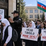 Azerbaycan'da okullardaki başörtüsü yasağına karşı öğrenci protestolarını konu alan temsili görsel. Güvenlik görevlisi başörtülü kız öğrencilerin okula girişini engellerken protestocu öğrenciler, “Başörtüsü eğitime engel değildir” ve “Herkesin eğitim hakkı vardır” sloganlarıyla eğitimde ayrımcılığa son verilmesini talep ediyor.