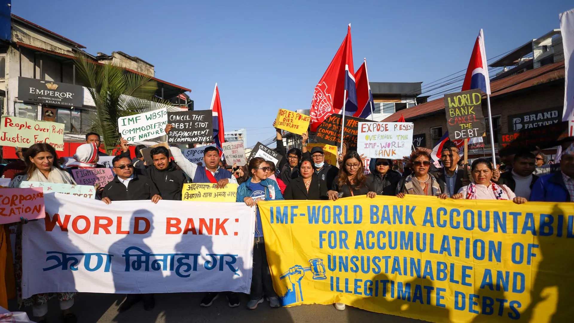 Uluslararası Para Fonu ve Dünya Bankasına karşı pankartlar taşıyarak borçların silinmesini isteyen protestocular; uluslararası finans kuruluşlarının politikalarını gelişmekte olan ülkelerde borç, enflasyon ve ekonomik baskının ağırlaşmasından sorumlu tutan eleştirileri simgeleyen bir görüntü.