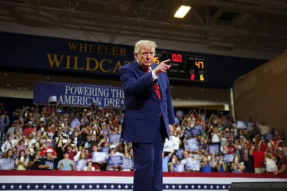 Donald Trump bir seçim mitinginde sahneden destekçi kalabalığına işaret ediyor; ABD ara seçimleri öncesinde Cumhuriyetçi seçmenleri harekete geçirme çabasını yansıtan bir görüntü.